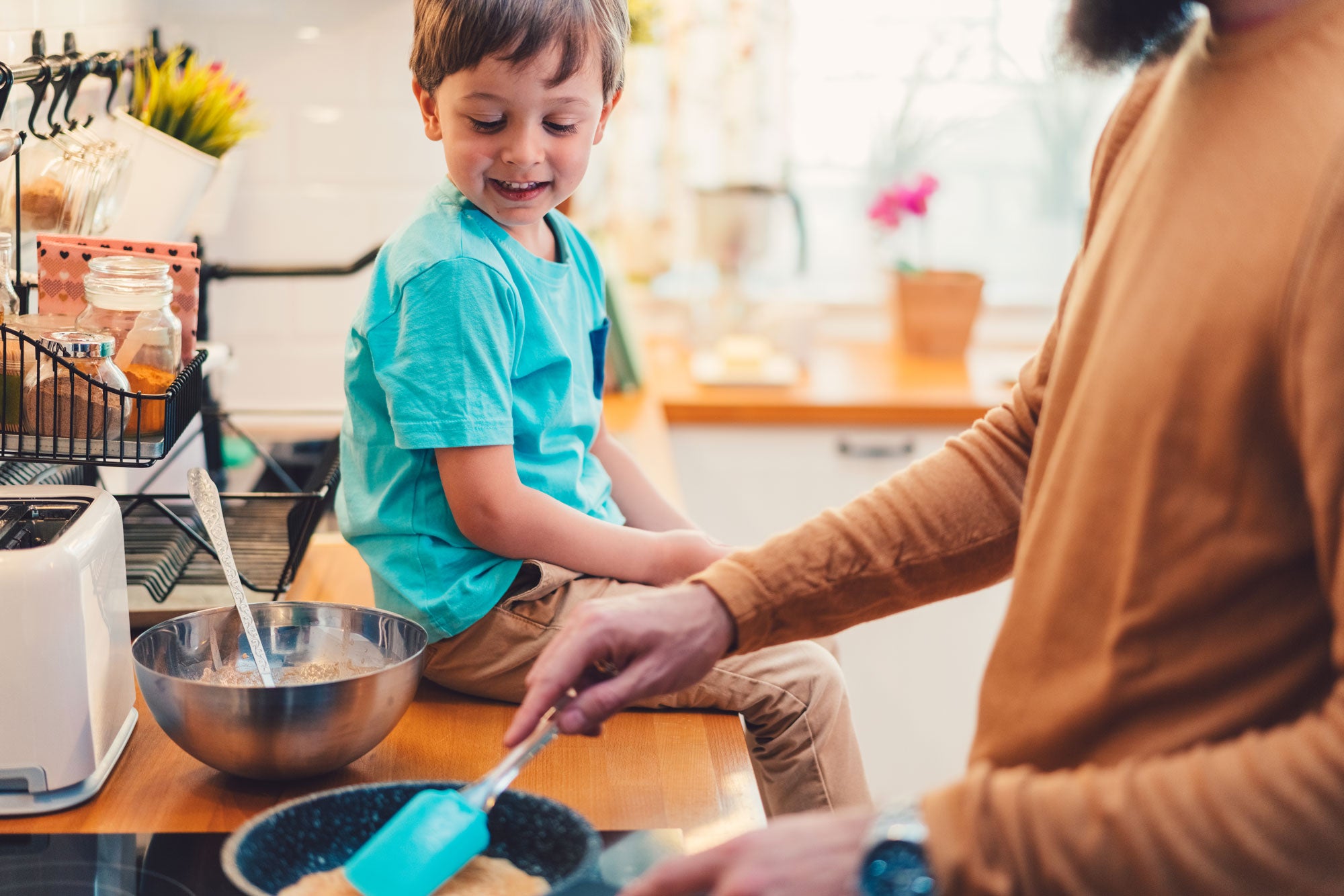 Boy watching dad make pancakes at home