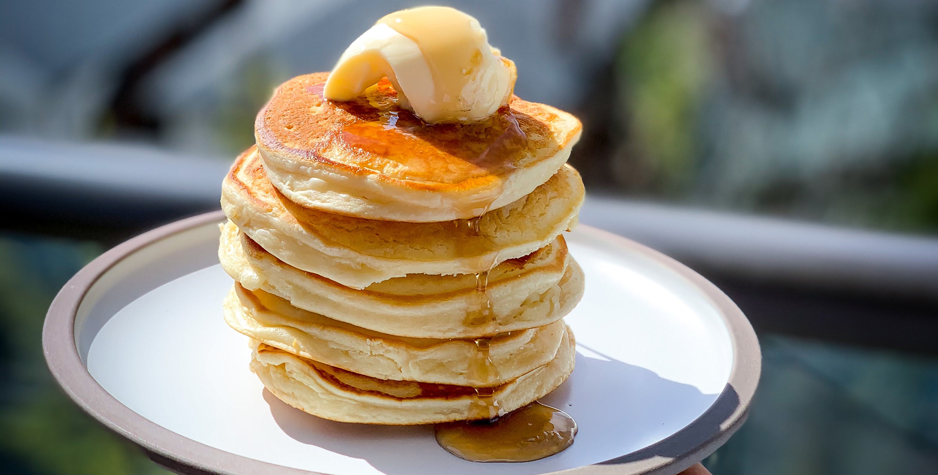 Stack of fluffy pancakes topped with butter and syrup